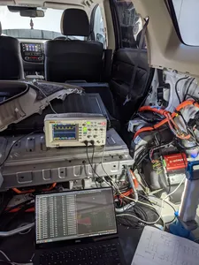 View inside the rear of an Outlander PHEV parked in my shed with a laptop, CAN analyser device, and oscilloscope all connected